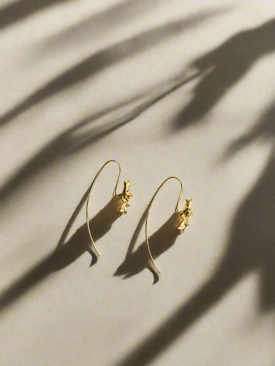 Gold earrings on a textured black surface