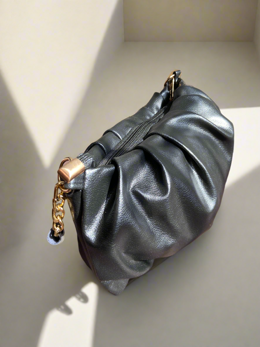 Black handbag with a gold chain on a light background