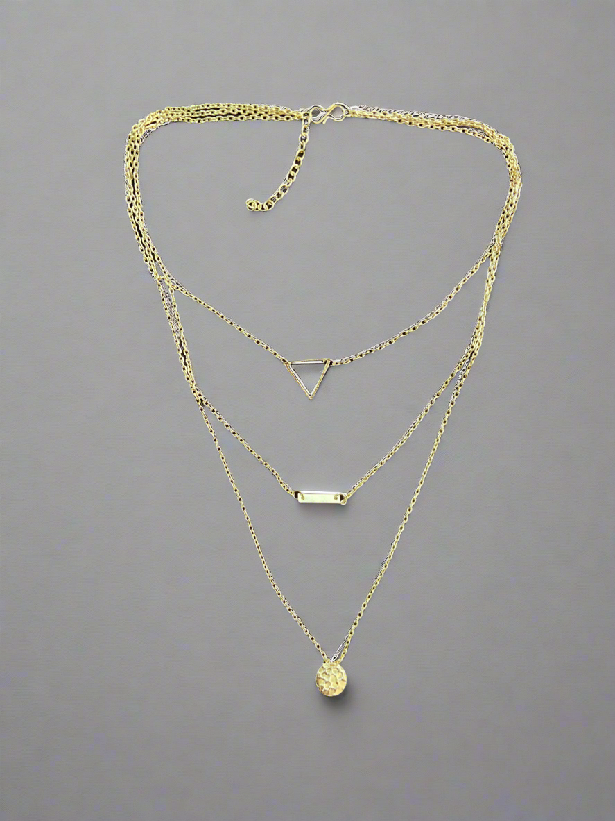 Gold necklace with multiple pendants on a gray background