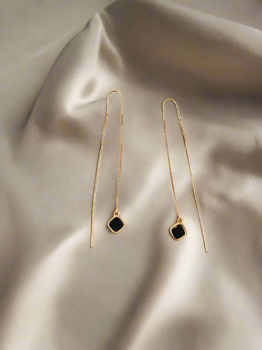 Two gold jewelry components on a textured black surface