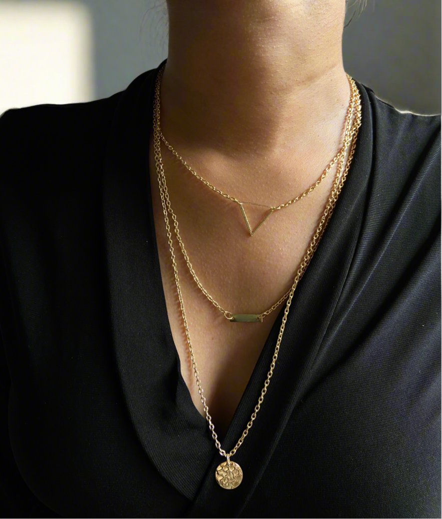 Gold necklaces with geometric pendants on a black outfit