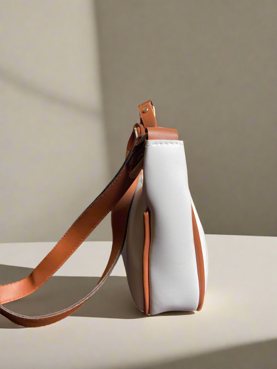 White handbag with brown strap on a neutral background