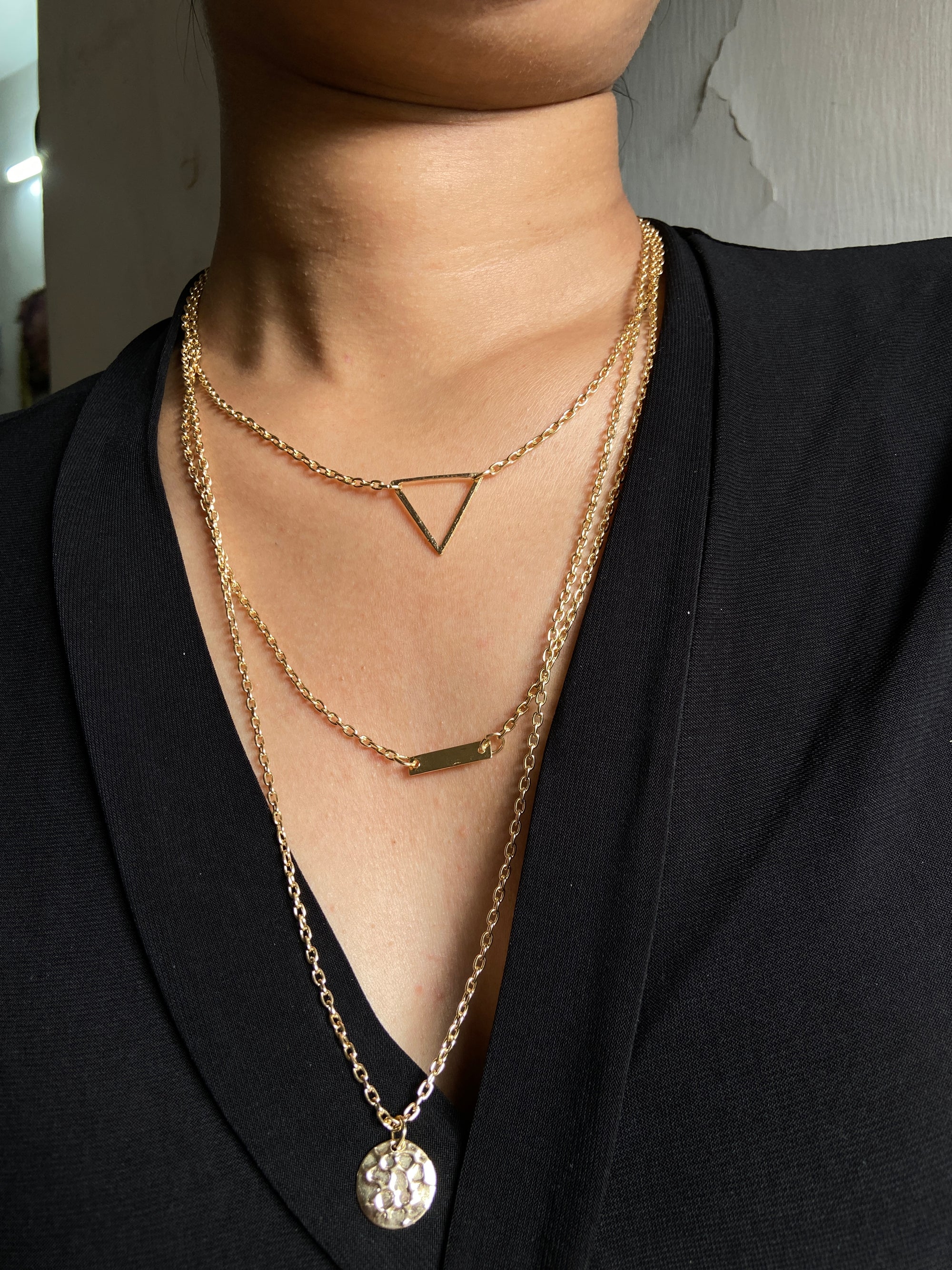 Gold necklace with multiple pendants on a person wearing black