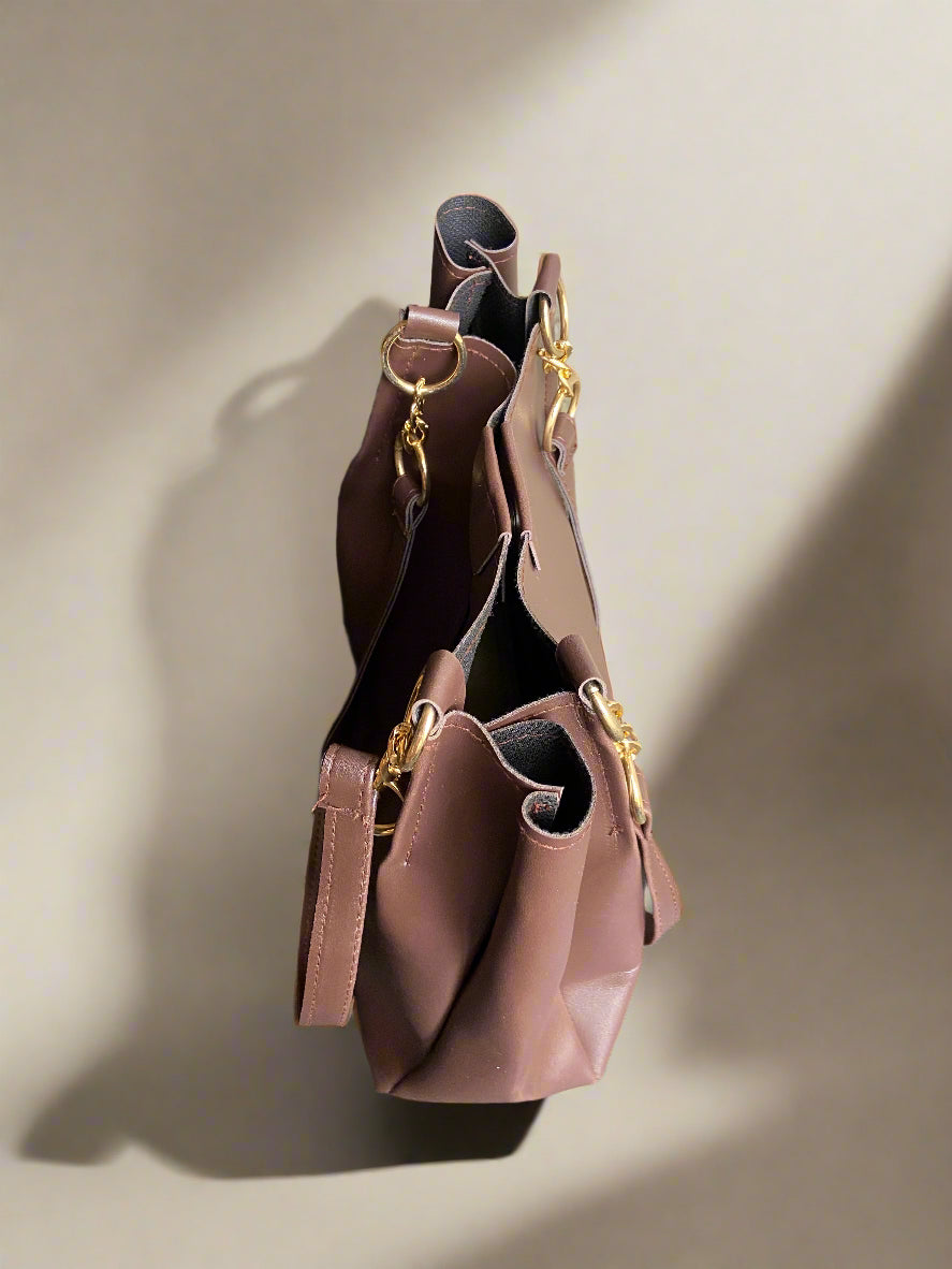Brownhandbag with gold accents on a beige background