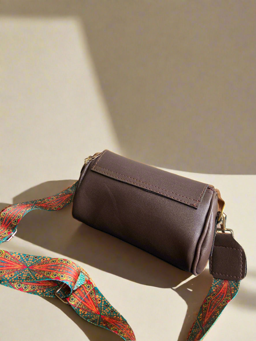 Brown Boho leather handbag with a colorful strap on a beige background