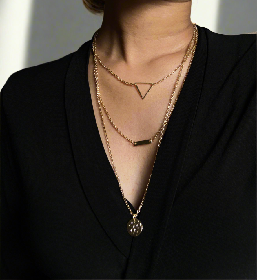 Close-up of a person wearing gold necklaces with a plain background