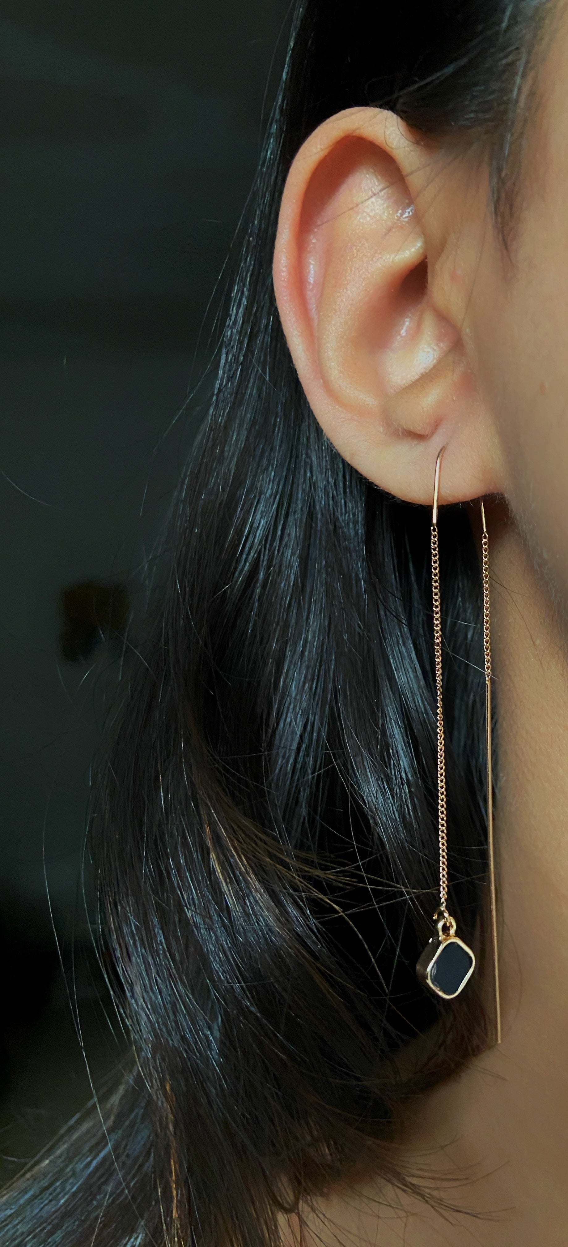 Close-up of an earring worn by a person with dark hair.