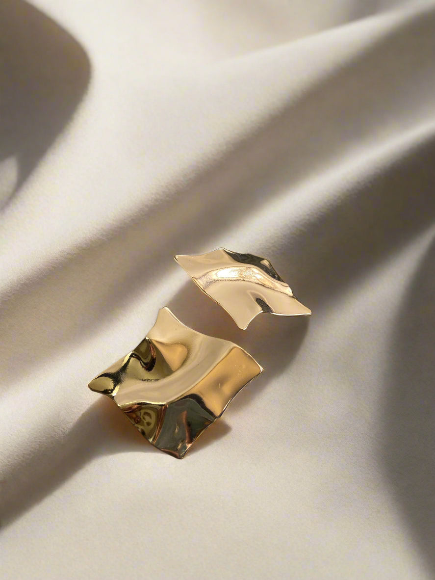 Gold earrings on a textured black surface