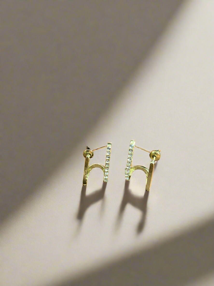 Gold bar earrings on a dark fabric background