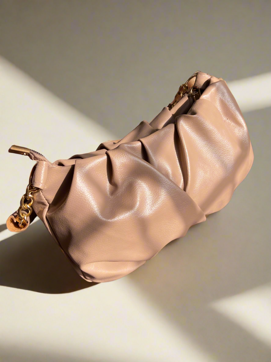 Beige handbag with gold chain detail on a light background