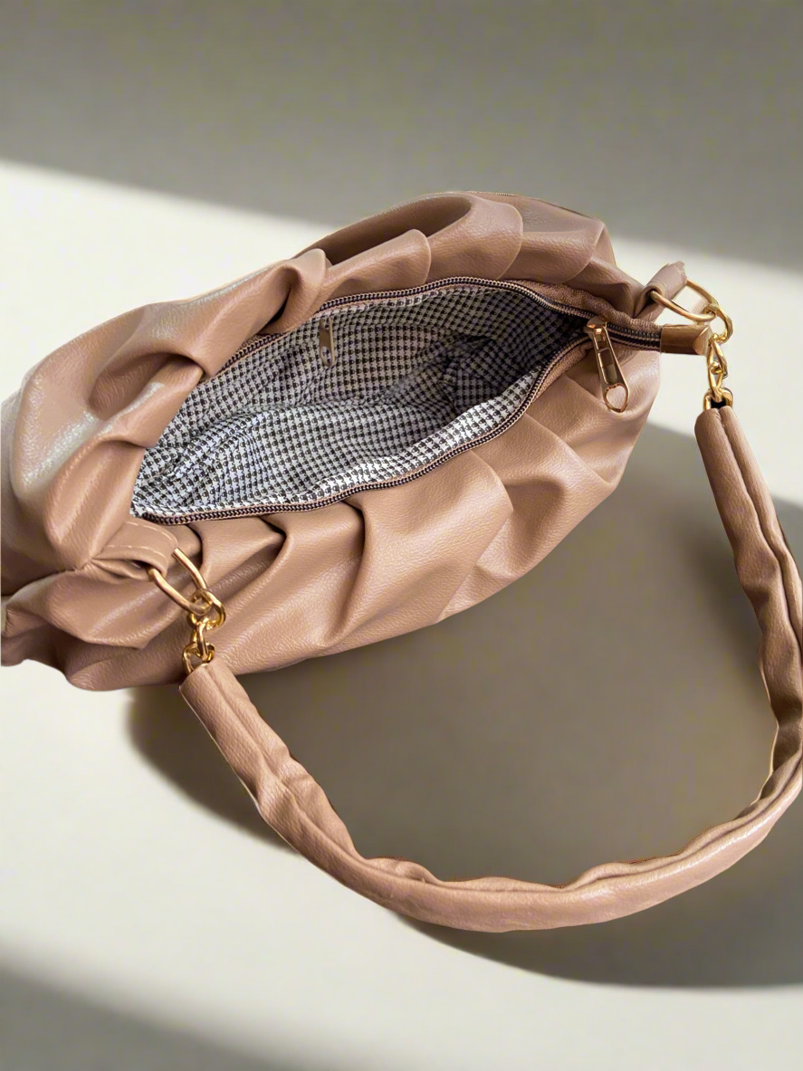 Beige handbag with a gold zipper on a light background