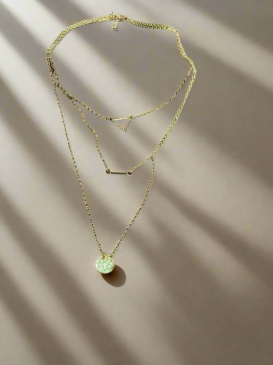 Gold necklace with multiple pendants on a gray background