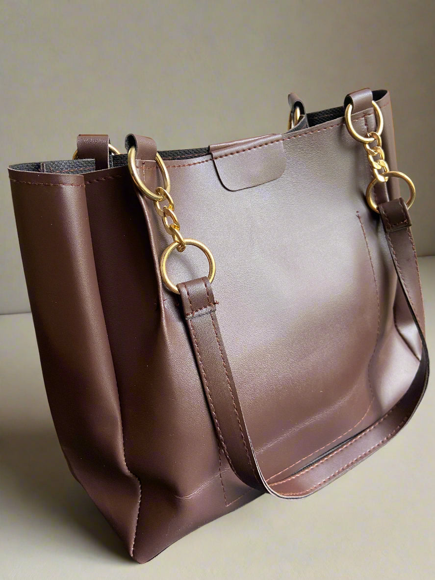 Brown leather handbag with gold hardware on a neutral background