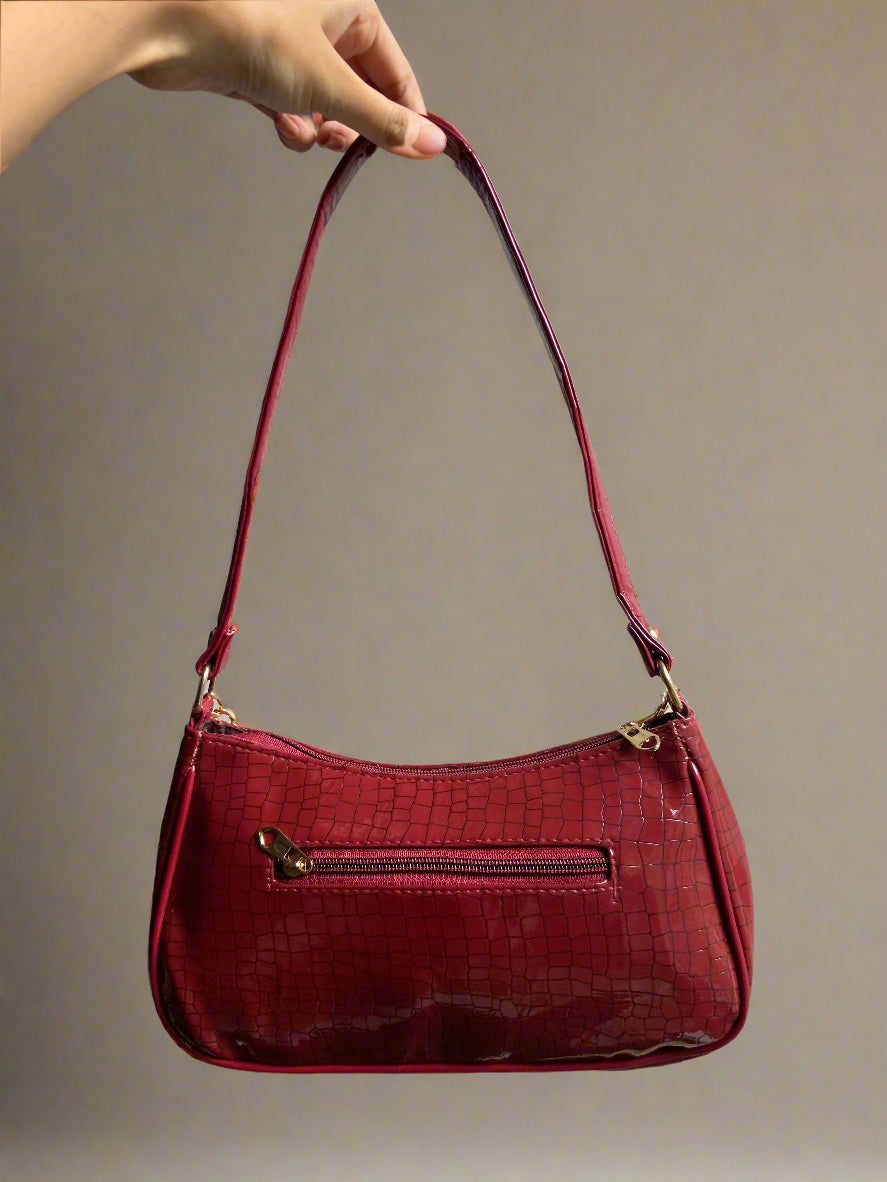 Red handbag held by a hand against a gray background